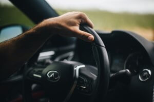 A driver's hand on a car steering wheel