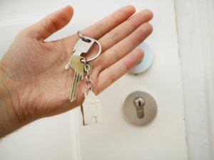 A close up photo of a hand holding keys in front of the home door