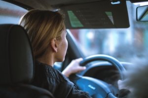 A closeup of a female driving a vehicle with her hand on the wheel