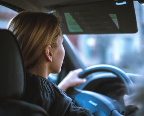 A closeup of a female driving a vehicle with her hand on the wheel