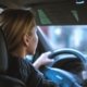 A closeup of a female driving a vehicle with her hand on the wheel
