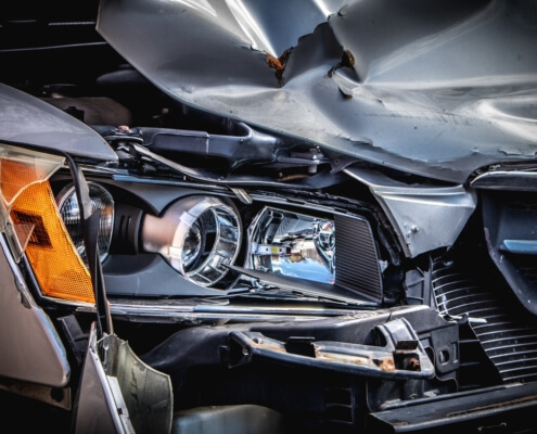 A close up of a damaged car headlight & car hood