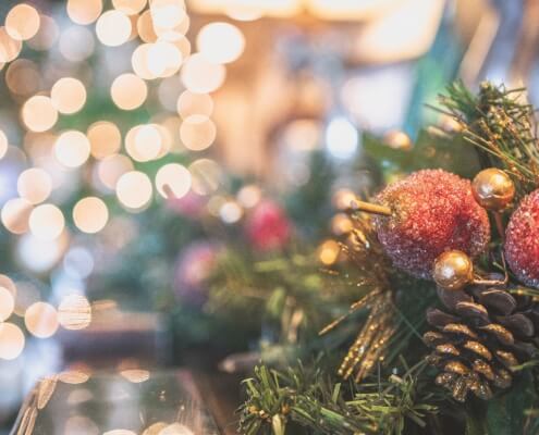 A close up of a Christmas tree with blurred holiday lights in the background