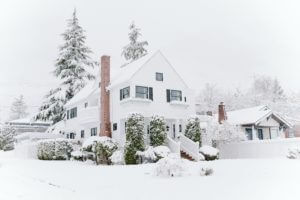 A winter scene of a home in a winter setting with snow and fog.