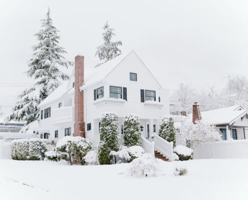 A winter scene of a home in a winter setting with snow and fog.