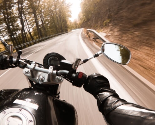 Photo of a person riding a motorcycle with the view behind the wheel