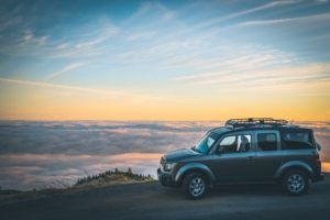 A small suv vehicle parked on the side of the road with an ocean in the background