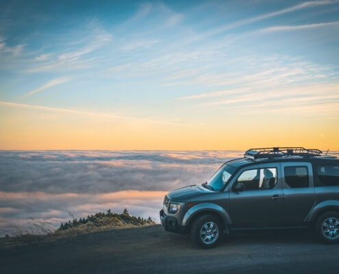 A small suv vehicle parked on the side of the road with an ocean in the background