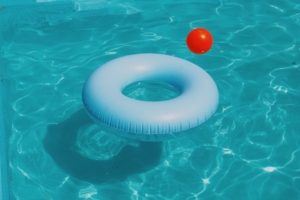 A closeup of water in a swimming pool with a flotation device & a pool toy