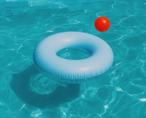 A closeup of water in a swimming pool with a flotation device & a pool toy