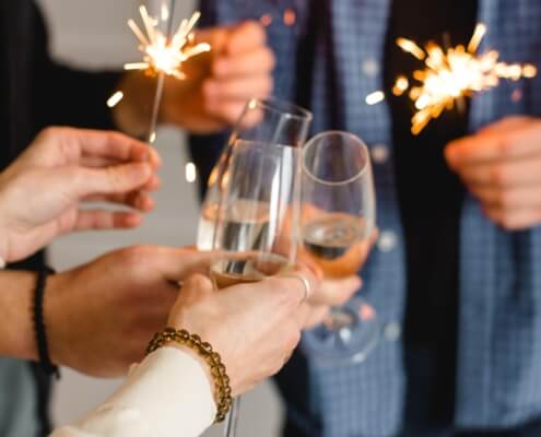 A closeup of wine glasses and New Year's Eve sparklers