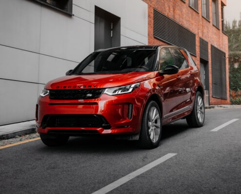 A photo of a red SUV on a side street